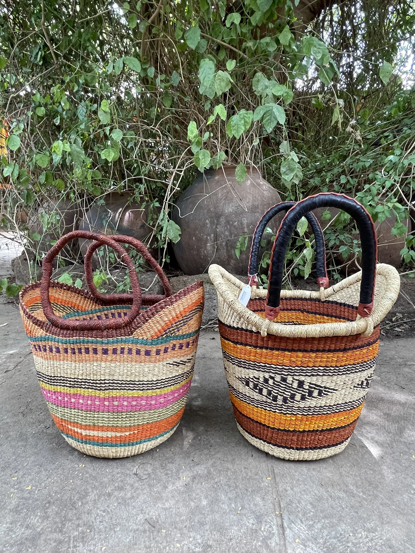 Two two-handled baskets side by side: exposed straw handles on the left and leather-covered handles on the right.