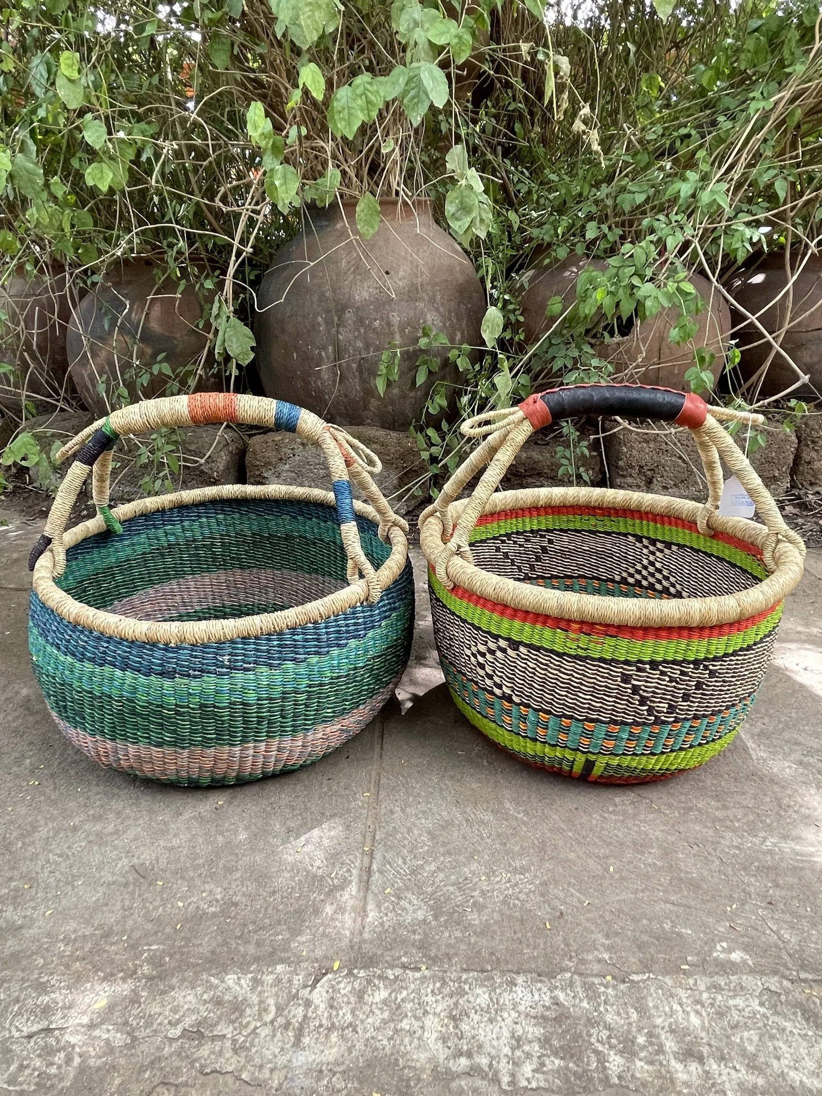 Two round baskets side by side, showing differences in the top coils and in straw and leather handle finishing.