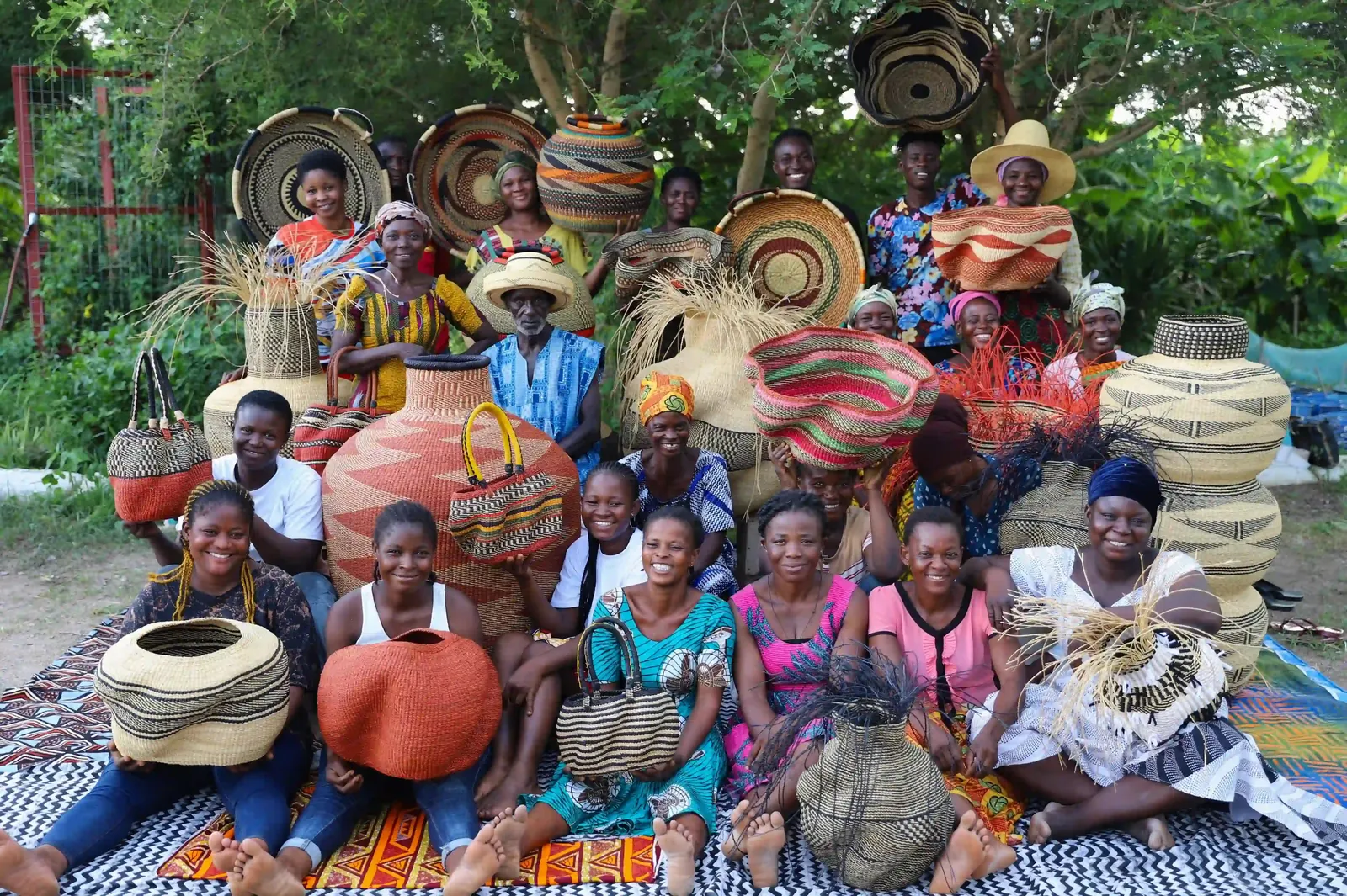 A group of Baba Tree weavers with baskets, hats and other woven work.